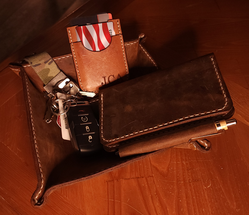Custom leather accessories including key holder, card wallet, and pen case on a leather tray