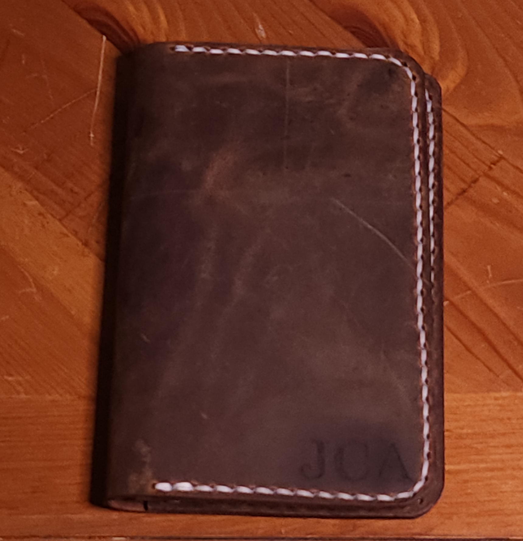 Fox Tree Creations full grain leather field notes cover in dark brown with white stitching on wooden surface